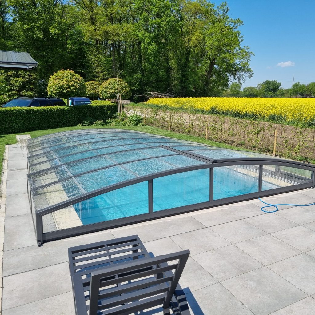 Pool mit Abdekcung neben einer gelben Wiese und einer Sonnenliege