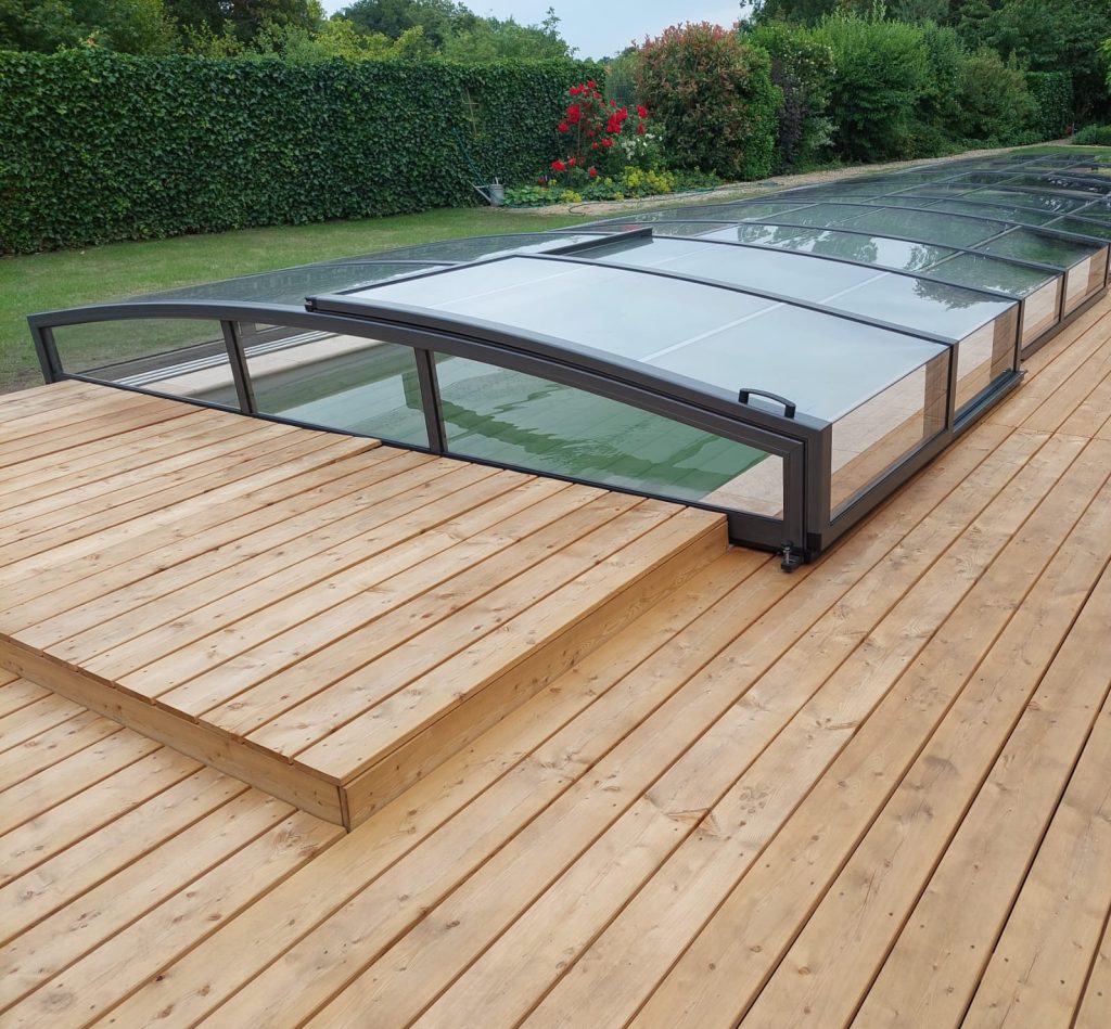 Eine Glasabdeckung überdeckt den Pool. Rundum ist eine Terrasse